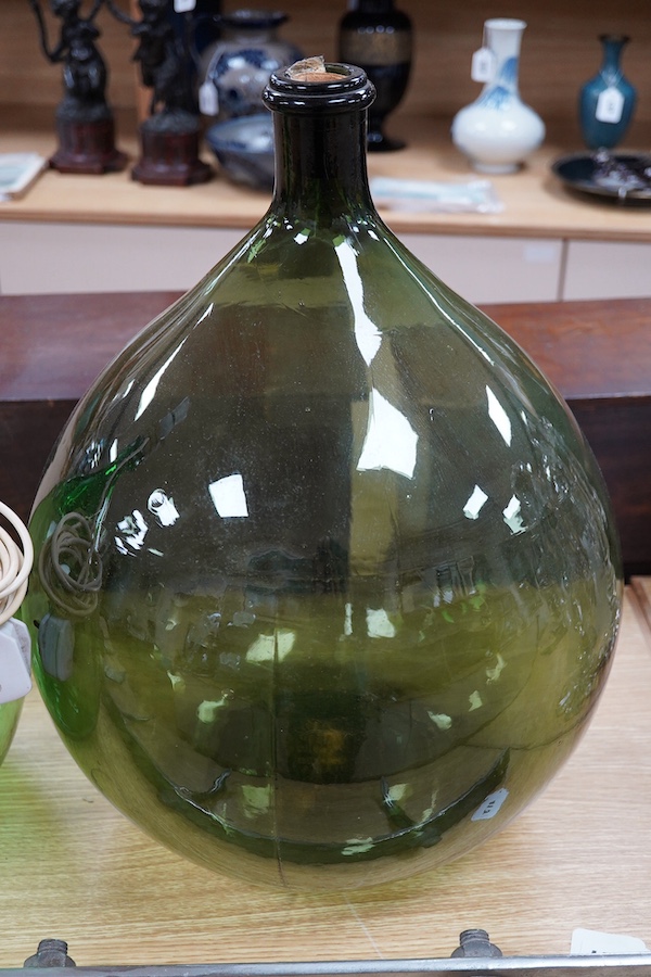 Two green glass carboys, one converted to a lamp, 58cm high overall. Condition - good, untested